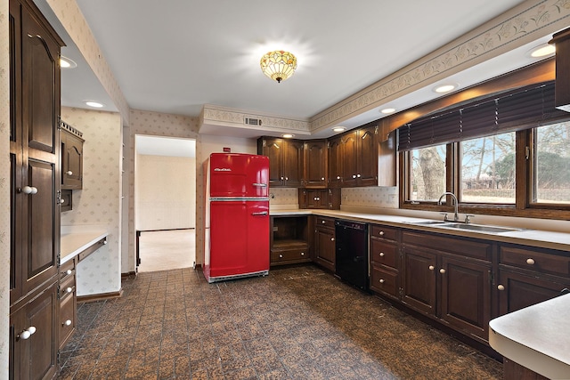 kitchen featuring refrigerator, a sink, black dishwasher, light countertops, and wallpapered walls