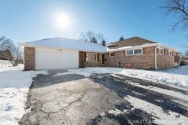 view of front of house featuring driveway, an attached garage, a chimney, and brick siding