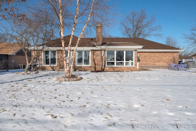 snow covered property featuring brick siding