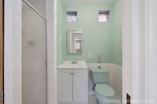 full bath with toilet, a wainscoted wall, vanity, a shower stall, and tile walls