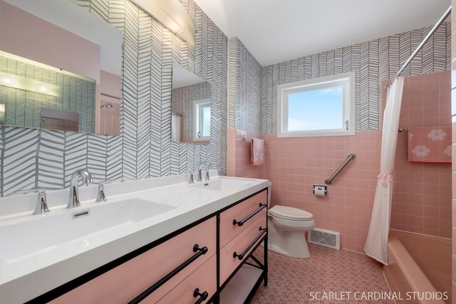 full bath with visible vents, a sink, tile walls, and double vanity