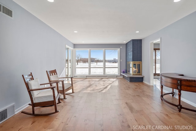 sitting room with light wood finished floors, baseboards, a fireplace, and visible vents