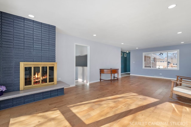 living room featuring baseboards, a fireplace, wood finished floors, and recessed lighting