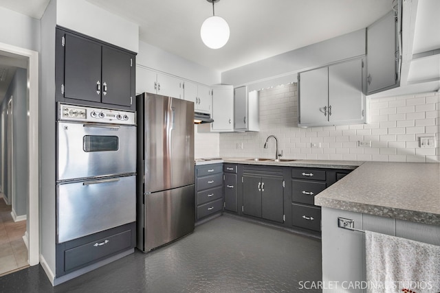 kitchen with decorative backsplash, decorative light fixtures, stainless steel appliances, under cabinet range hood, and a sink