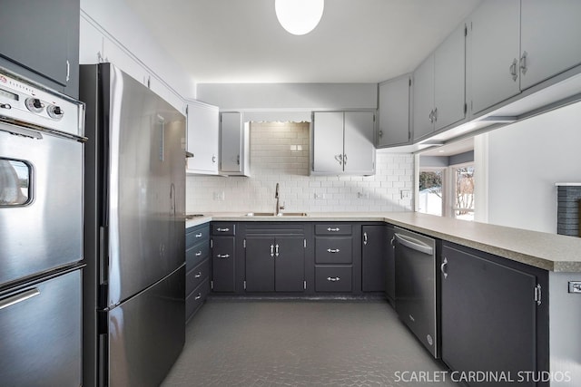 kitchen featuring a sink, a peninsula, appliances with stainless steel finishes, and light countertops