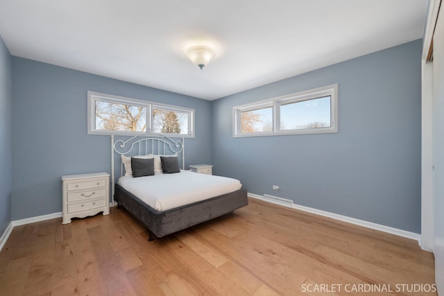 bedroom featuring light wood-type flooring, visible vents, and baseboards