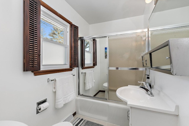 bathroom featuring vanity, toilet, and bath / shower combo with glass door