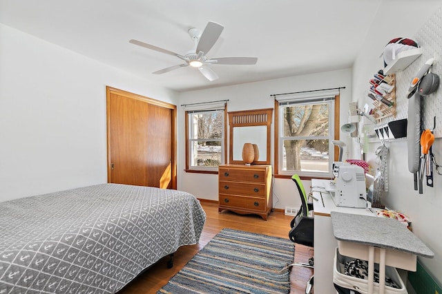 bedroom with baseboards, visible vents, a ceiling fan, wood finished floors, and a closet