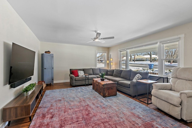 living area with a ceiling fan, baseboards, and wood finished floors