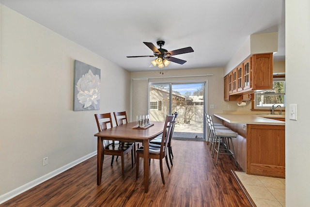 dining space featuring a ceiling fan, a wealth of natural light, dark wood-style flooring, and baseboards