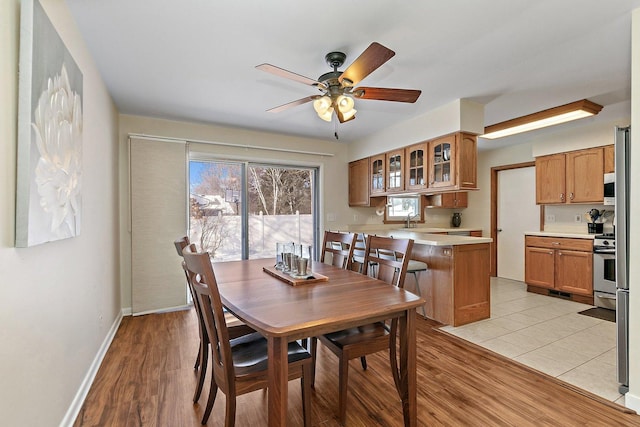 dining space with baseboards, ceiling fan, and light wood-style floors