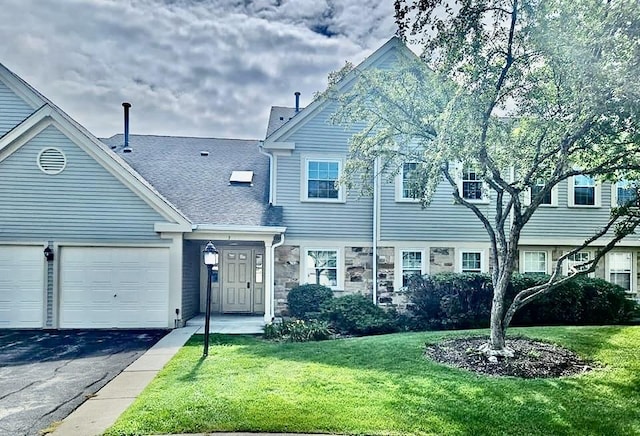 view of front facade featuring an attached garage, a shingled roof, aphalt driveway, and a front yard