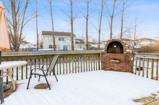 snow covered deck with a residential view and fence