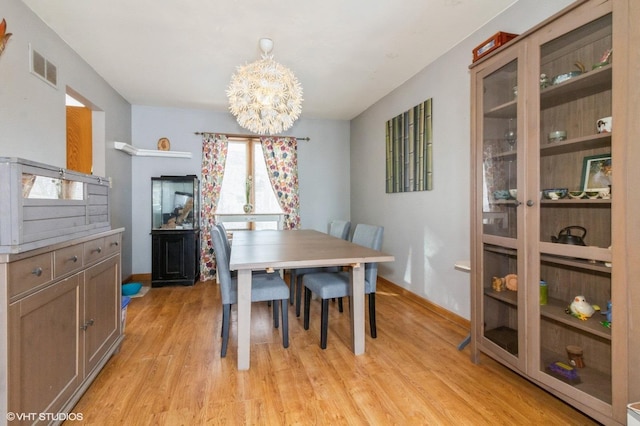 dining space featuring a chandelier, light wood-style flooring, visible vents, and baseboards