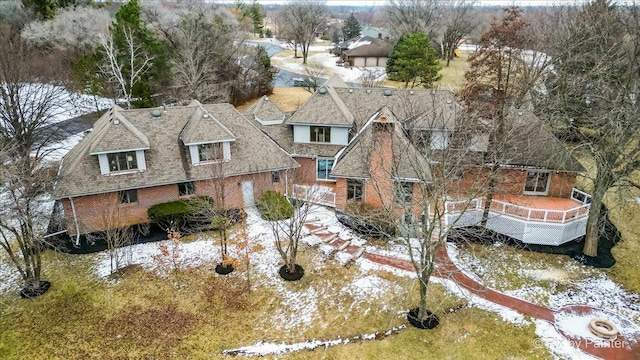 snow covered property with a deck and brick siding