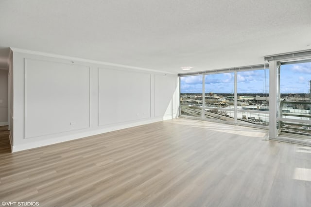 unfurnished living room with light wood-style floors, floor to ceiling windows, a decorative wall, and a textured ceiling