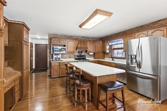 330 Fox Trl, Bourbonnais, IL 60914 - kitchen with appliances with stainless steel finishes, light countertops, custom range hood, a breakfast bar area, and dark wood-type flooring
