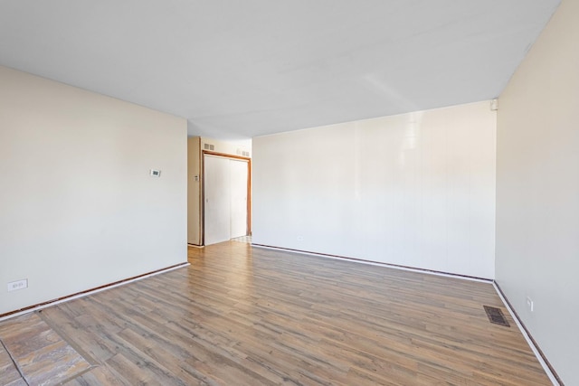 empty room with light wood-type flooring and visible vents