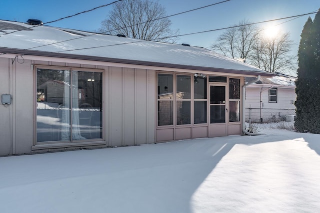 snow covered house featuring fence