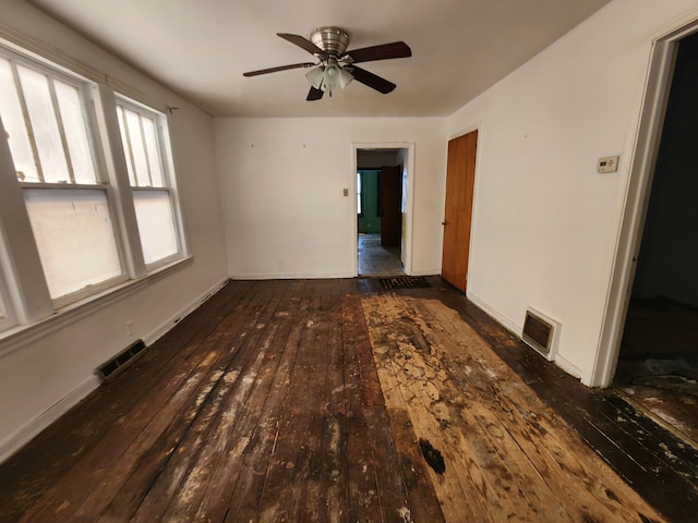 unfurnished room featuring a ceiling fan, dark wood finished floors, visible vents, and baseboards