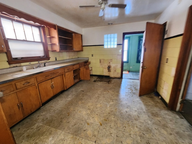 kitchen featuring open shelves, brown cabinetry, a sink, and a ceiling fan