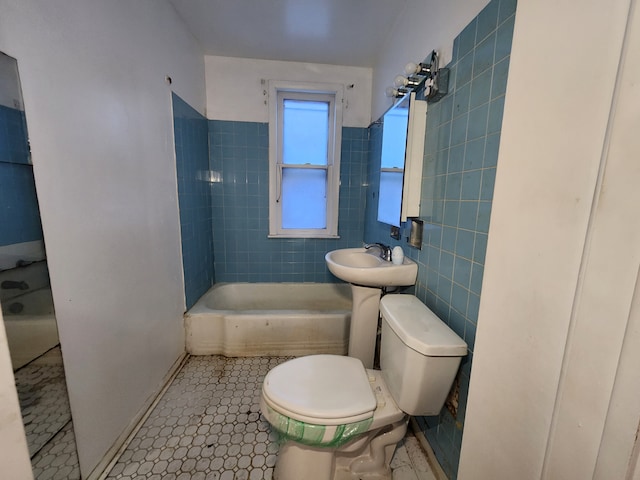 bathroom featuring tile walls, shower / bath combination, toilet, a sink, and tile patterned flooring