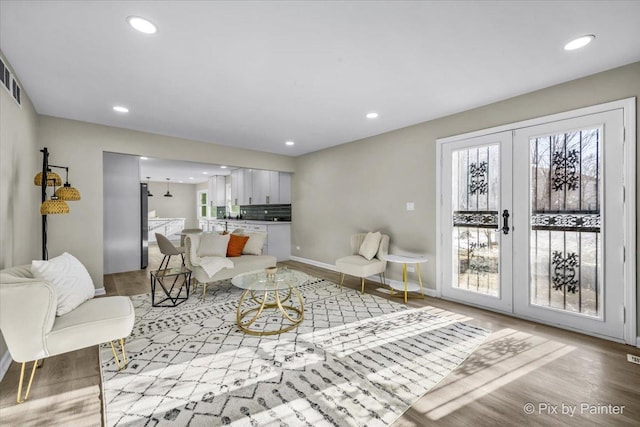 living room featuring recessed lighting, french doors, light wood-style flooring, and baseboards