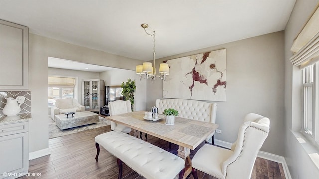 dining room with dark wood-style flooring, a notable chandelier, and baseboards