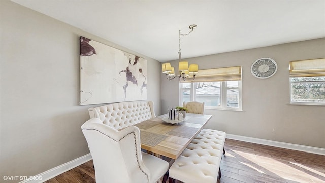 dining area featuring a notable chandelier, baseboards, and wood finished floors