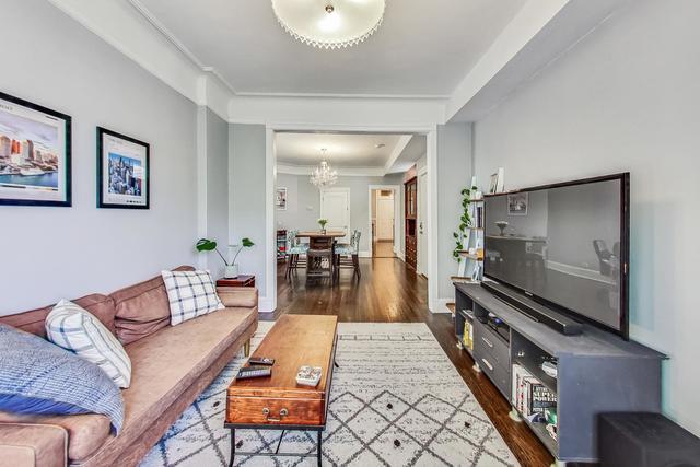 living room with a raised ceiling, ornamental molding, wood finished floors, a chandelier, and baseboards