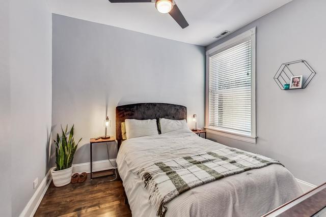 bedroom with a ceiling fan, visible vents, baseboards, and wood finished floors