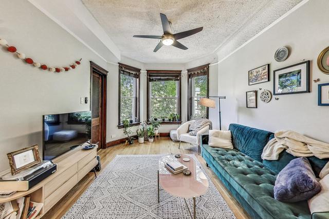 living area with a textured ceiling, ceiling fan, wood finished floors, and baseboards