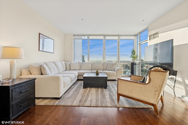 living room featuring a wall of windows, visible vents, and wood finished floors