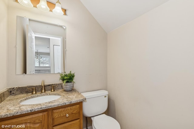 bathroom with toilet, vaulted ceiling, and vanity