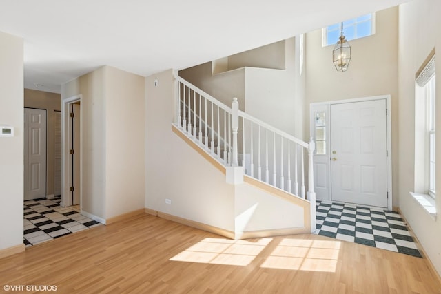 foyer featuring baseboards, a notable chandelier, stairway, and wood finished floors