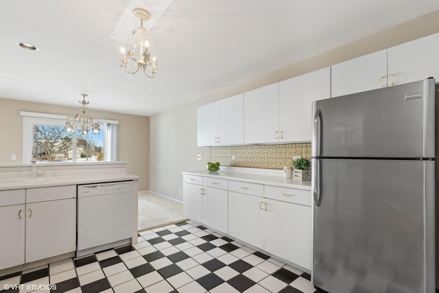 kitchen with freestanding refrigerator, decorative light fixtures, white dishwasher, and white cabinetry