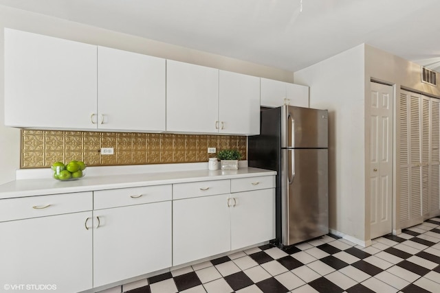 kitchen with light floors, light countertops, visible vents, freestanding refrigerator, and white cabinetry