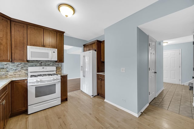 kitchen with baseboards, white appliances, light wood-style flooring, and tasteful backsplash