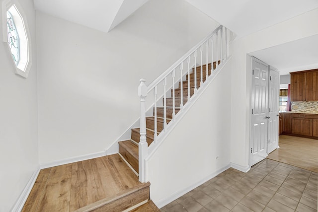 stairs featuring wood finished floors and baseboards