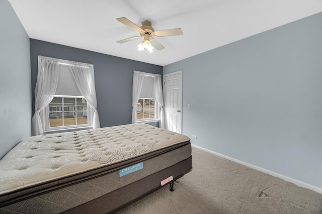 carpeted bedroom with ceiling fan and baseboards