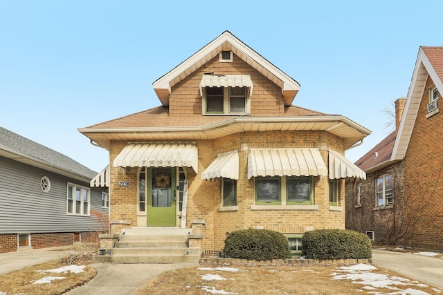 view of front of house with brick siding and roof with shingles