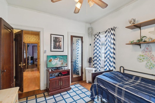 bedroom featuring crown molding, a ceiling fan, and wood finished floors