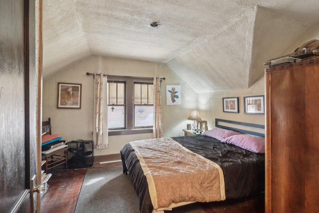 bedroom with lofted ceiling, dark wood-style flooring, and a textured ceiling