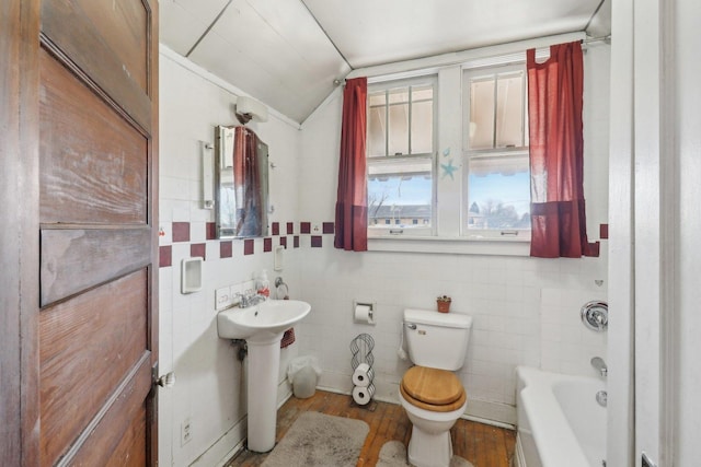 full bathroom featuring toilet, a sink, wood finished floors, vaulted ceiling, and a tub