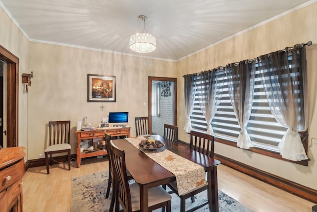 dining room featuring light wood-type flooring, baseboards, ornamental molding, and a chandelier