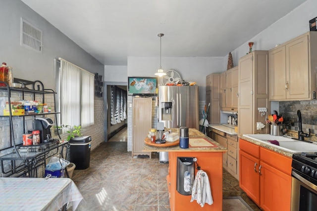 kitchen featuring stainless steel appliances, a sink, a kitchen island, visible vents, and pendant lighting