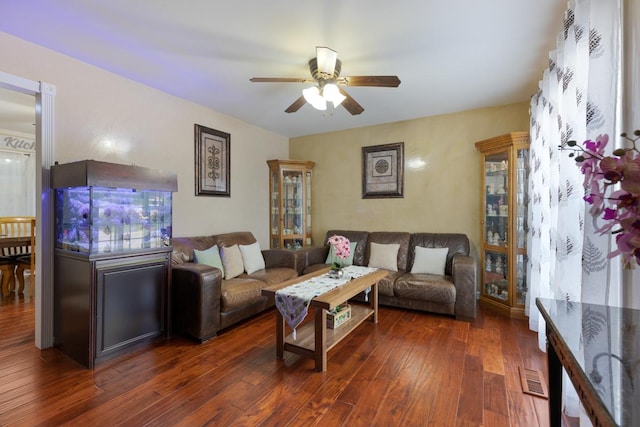 living area with dark wood-type flooring, visible vents, and a ceiling fan