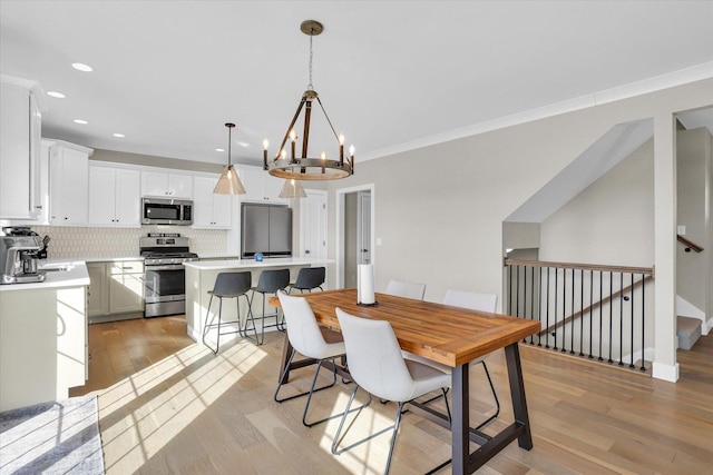 dining room with a notable chandelier, recessed lighting, light wood-style floors, ornamental molding, and stairway