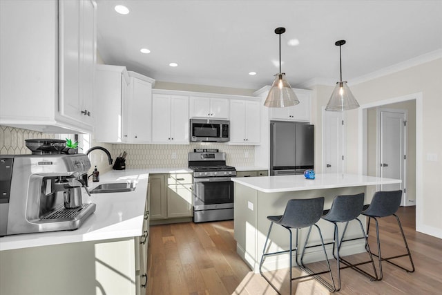 kitchen featuring a breakfast bar area, a sink, white cabinetry, light countertops, and appliances with stainless steel finishes