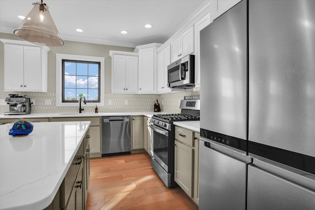 kitchen featuring light stone counters, light wood finished floors, stainless steel appliances, decorative backsplash, and a sink